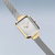 Reloj de mujer con esfera rectangular plateada, bordes dorados y pulsera Milanesa