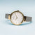 "Reloj de mujer en vista lateral: bisel dorado, pulsera milanesa plateada"
