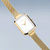 "Reloj de mujer en vista lateral: caja rectangular con bisel y correa dorados."