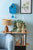 Reloj de pared azul en forma de casa de plástico en la pared con dos manecillas