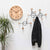 Reloj de pared redondo de madera con esfera de madera clara y manecillas negras, números romanos