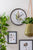 Reloj de pared con borde negro y motivo de hoja verde en la pared