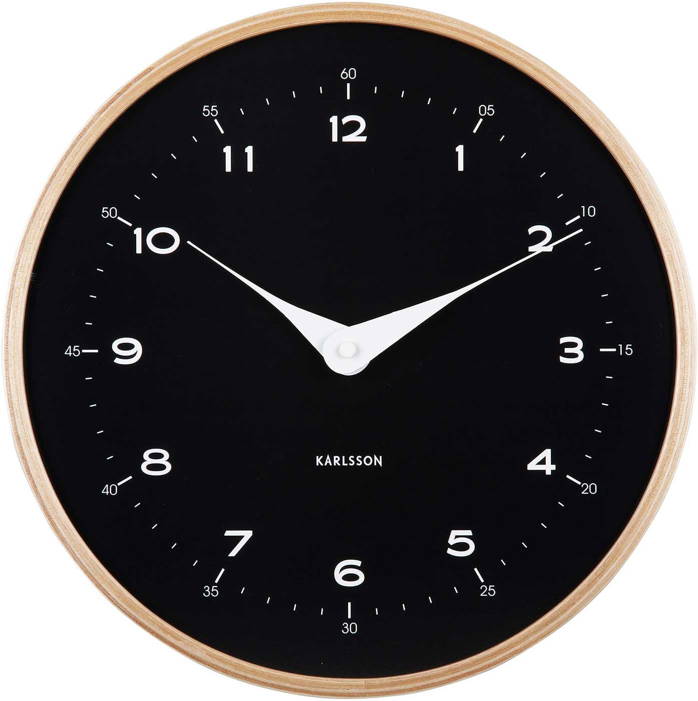 Reloj de pared con esfera negra, manecillas blancas y marco de madera clara, logo de Karlsson
