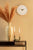Reloj de pared con marco de madera beige, esfera blanca y manecillas negras