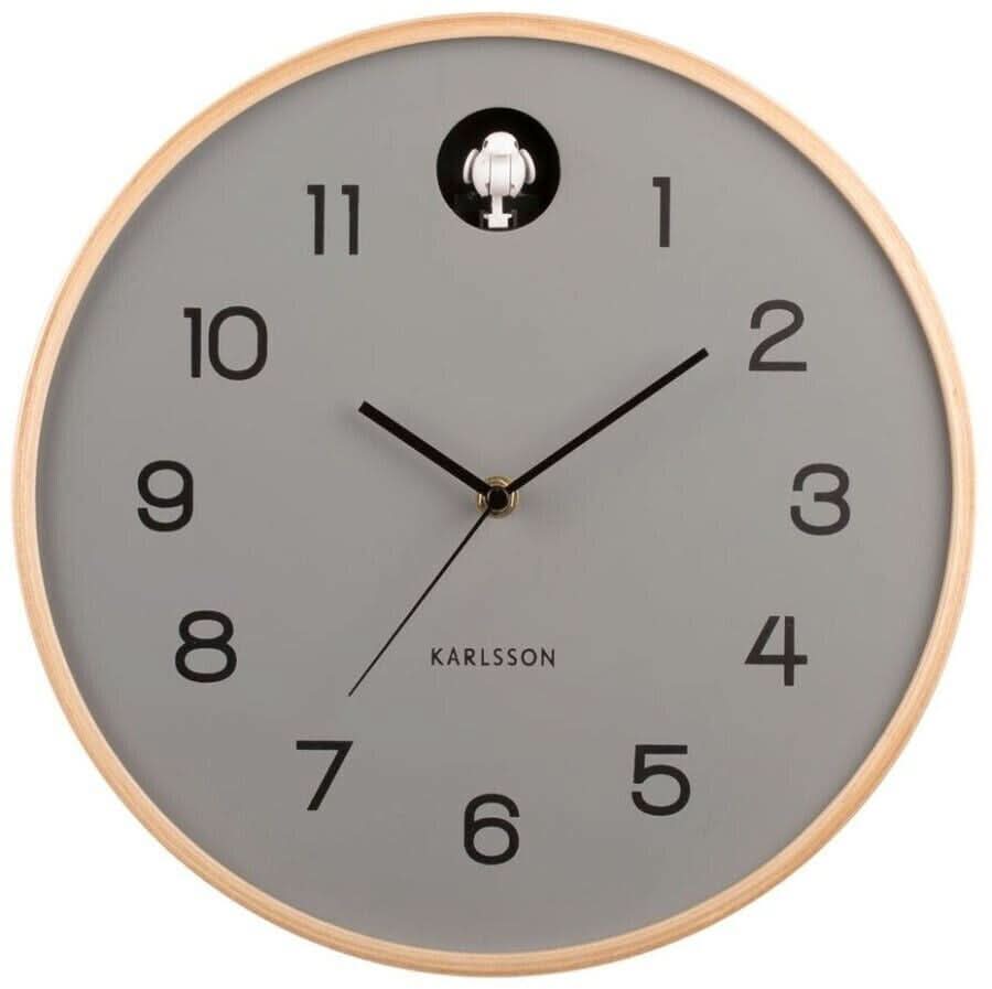Reloj de pared redondo con marco de madera clara y esfera gris, manecillas negras, figura de cuco