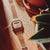 Reloj Casio para mujer con correa de metal plateado y pantalla digital sobre base de madera