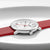 "Vista de cerca de reloj de mujer: esfera blanca sobre correa de cuero roja con corona de caja."