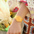 "Reloj de mujer en la muñeca con correa amarillo-naranja y esfera dorada"