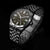 Pulsera de hombre con esfera oscura, manecillas redondas y brazalete de acero inoxidable.