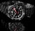 Reloj de buceo con esfera negra, manecillas rojas, índices luminosos y pulsera de acero inoxidable