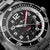 Reloj deportivo para hombre con esfera negra, manecilla central roja e indicador de fecha