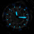 Reloj de hombre en la oscuridad: manecillas y marcadores luminiscentes azules sobre esfera negra