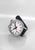 Reloj de hombre con correa de cuero negra, caja redonda plateada y esfera blanca
