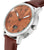Reloj de hombre, vista de cerca: caja plateada, correa de cuero marrón y esfera naranja