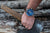 "Reloj de hombre en la muñeca con esfera azul y correa marrón."
