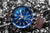Reloj de hombre con esfera azul, caja plateada y correa de cuero marrón.