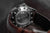 Reverso de un reloj de pulsera metálico para hombre con detalle del mecanismo y grabado