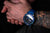 Reloj de buceo para hombre en la muñeca con correa azul y marcador de esfera luminosa