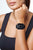 Smartwatch en la muñeca: pantalla negra, correa negra, bisel con detalles azules.