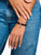 Pulsera de perlas con cuentas oscuras en la muñeca, con un pequeño colgante