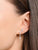 Pendientes con elementos de pedrería y colgante de perla en la oreja