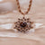 "Collar con cadena de oro rosa y colgante de sol con cabujón de madera marrón y detalles de joyería"