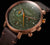 Reloj de hombre con esfera verde, detalles naranjas, correa de cuero marrón y pulsadores