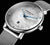 "Reloj de mujer con caja plateada, esfera blanca, agujas azules y correa de malla"