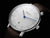 Reloj de mujer, vista de cerca, con esfera blanca, manecilla azul y correa de cuero marrón