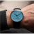 Reloj de hombre en la muñeca, esfera azul con manecillas negras y correa de cuero