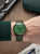Reloj de hombre en la muñeca: esfera verde, correa de cuero verde, caja en tono oro rosa.
