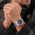 Pulsera de hombre en la muñeca, correa de acero inoxidable y esfera negra con aspecto de carbono