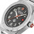 Reloj plateado para hombre con esfera negra, detalles rojos y números grandes.