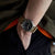 Reloj de hombre en la muñeca con esfera negra y correa de tela beige