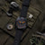Reloj de hombre con esfera oscura, detalles naranjas y correa textil con hebilla
