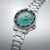 Reloj deportivo con esfera verde, correa de acero inoxidable, bisel negro y ventana de fecha LUN 6