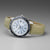 Reloj de hombre con correa de cuero beige, esfera plateada, bisel azul e índices