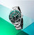 Reloj de hombre en vista de perfil con esfera verde, brazalete de acero plateado y corona