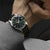 Reloj Seiko Presage para hombre en la muñeca, esfera verde oscuro, correa de cuero marrón.