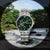 Reloj de hombre con esfera verde y apertura de corazón visible, brazalete de acero inoxidable