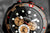 Reloj de hombre vista frontal: esfera negra con subesfera naranja y marcadores rojos
