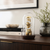 Reloj de mesa bajo cúpula de cristal con mecanismo dorado y base de madera oscura