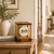 Reloj de mesa en aspecto de madera de cerezo con ventanas de cristal; mecanismo mecánico visible y números romanos