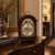 Reloj de mesa de madera con indicador de fases lunares y borde decorativo dorado sobre base de madera
