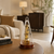 Reloj de mesa con campana de cristal y mecanismo dorado sobre mesa redonda, base de madera marrón
