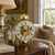 Reloj de mesa con campana de cristal dorada y esfera romana sobre pies metálicos