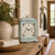 Reloj de mesa de madera con carcasa azul claro y decoración floral en la esfera, sobre superficie de madera