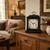 Reloj de mesa sobre cómoda de madera, caja negra, esfera blanca con flores, asa dorada