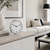 Reloj de mesa con esfera blanca, números negros y marco cromado sobre mueble