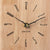 Nahaufnahme Zifferblatt der Wanduhr aus hellem Holz mit schwarzen Zeigern und goldfarbenem Zentrum